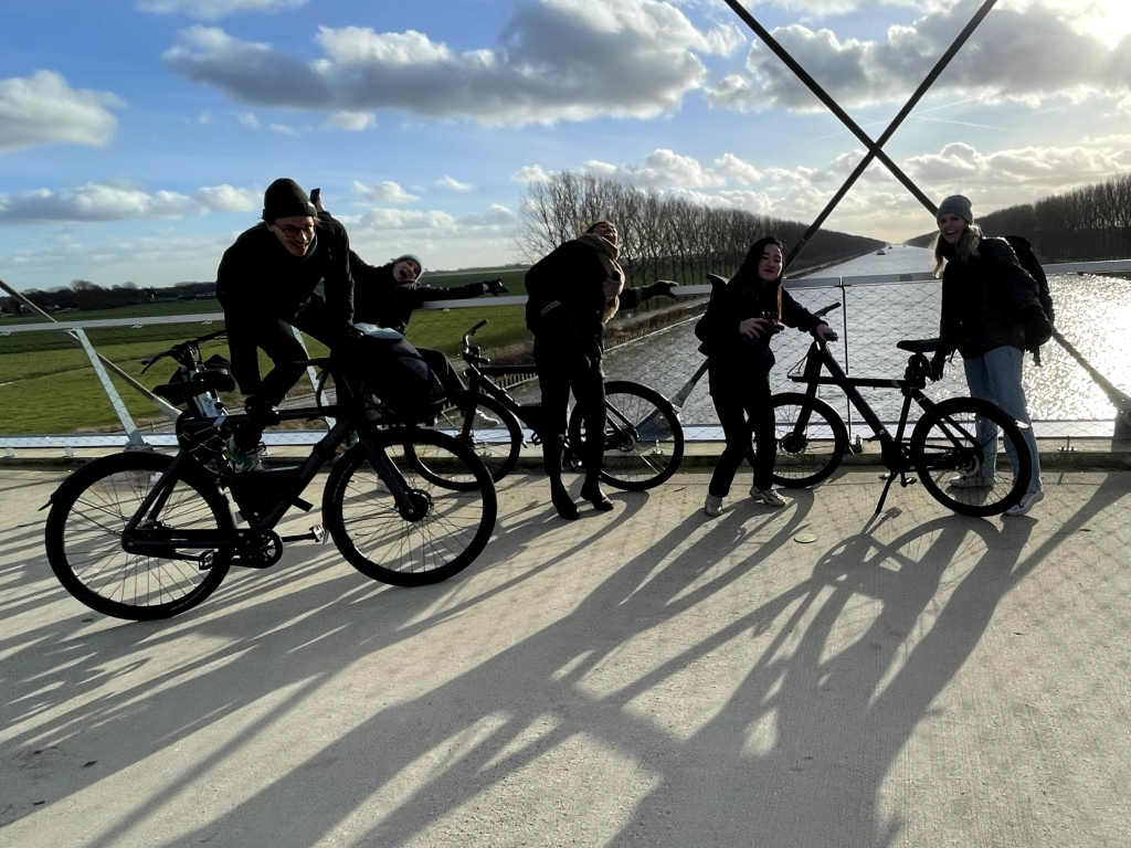 a team riding e-bikes on a tree-lined path alongside a canal